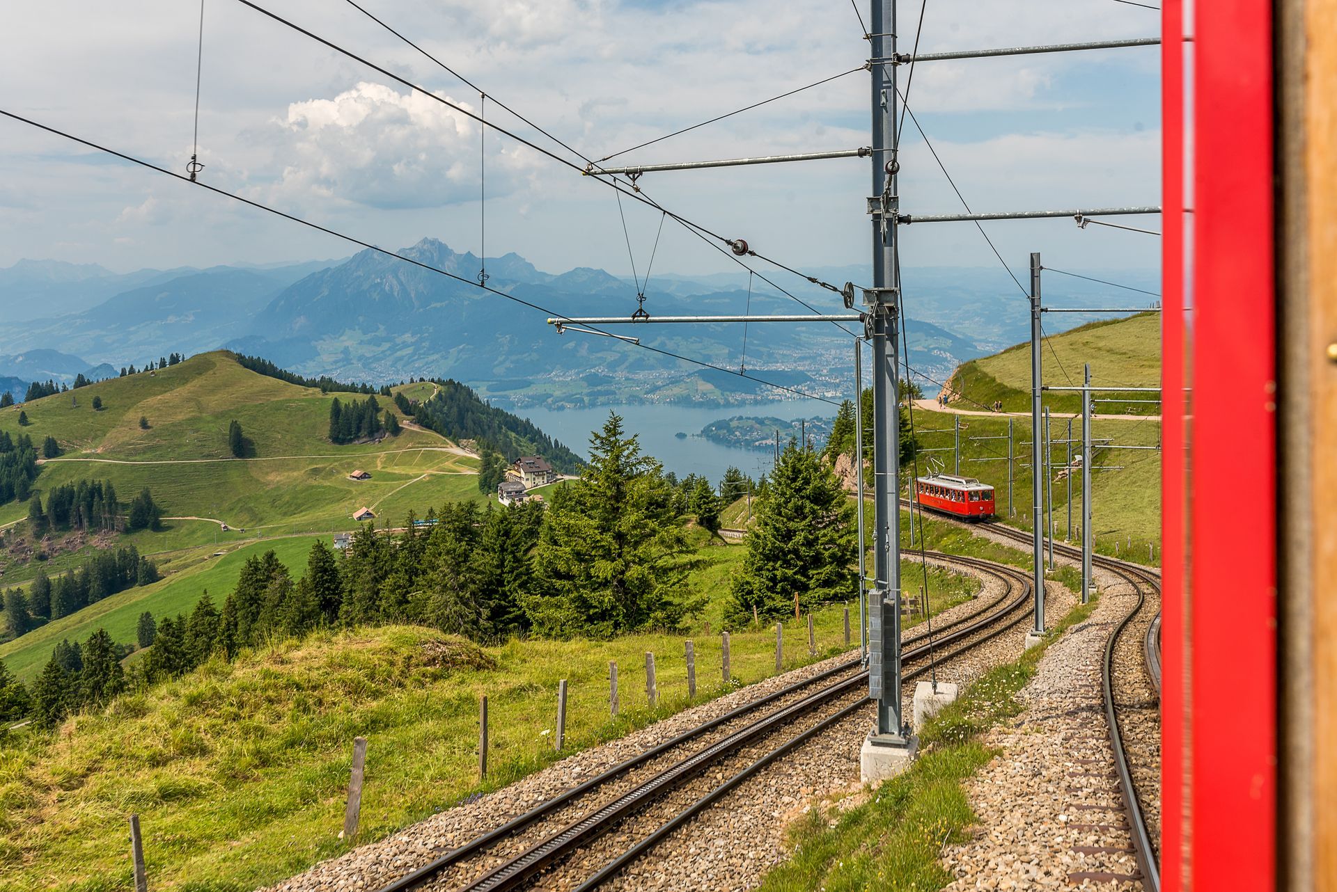 Red train in the mountains. Beautiful landscape with red train, railway, trees and mountain outside the train window on Rigi Mountain, Lucerne, Switzerland. 